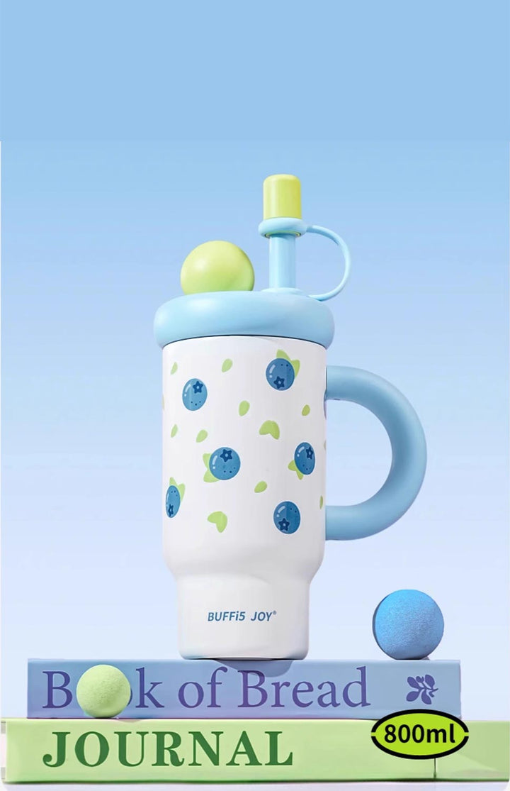 Strawberry print blue bottle standing on book with blue background, creative display