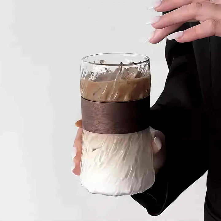 Woman holding elegant glass cup with iced mocha, showcasing refined and stylish design