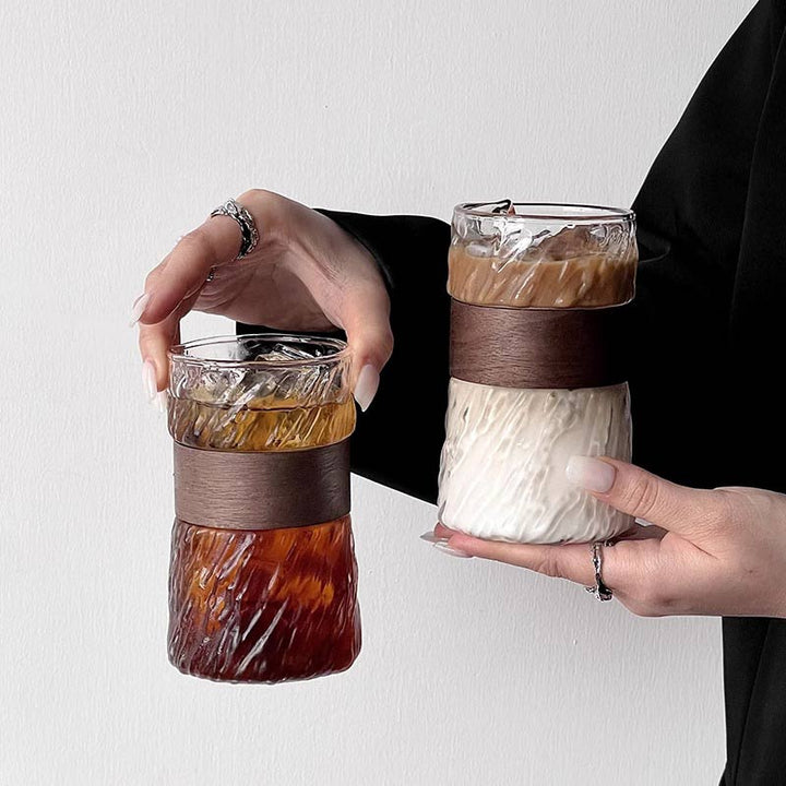Iced Americano and Mocha in glass cups with wooden detail held by woman, stylish coffee setup