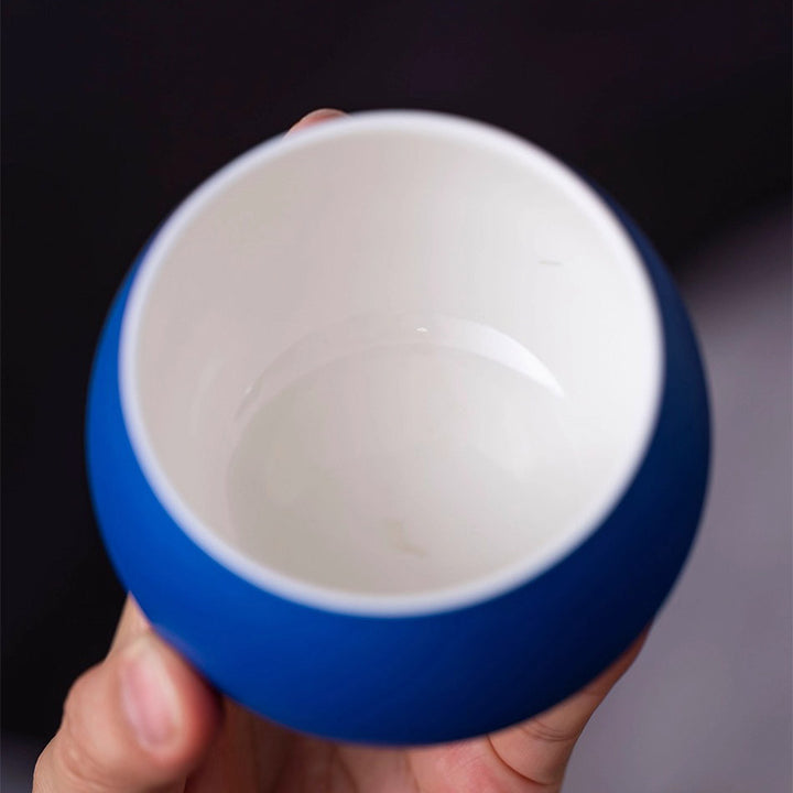 Close-up of woman holding Klein blue ceramic cup, showing elegant refined interior details