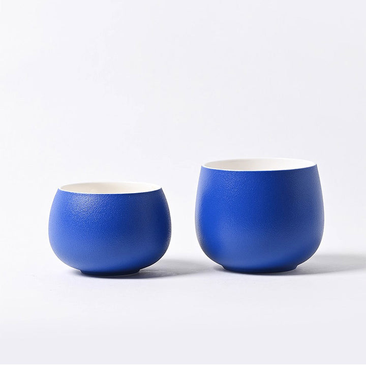 Two Klein blue ceramic coffee cups on minimal white background, highlighting elegant refined design