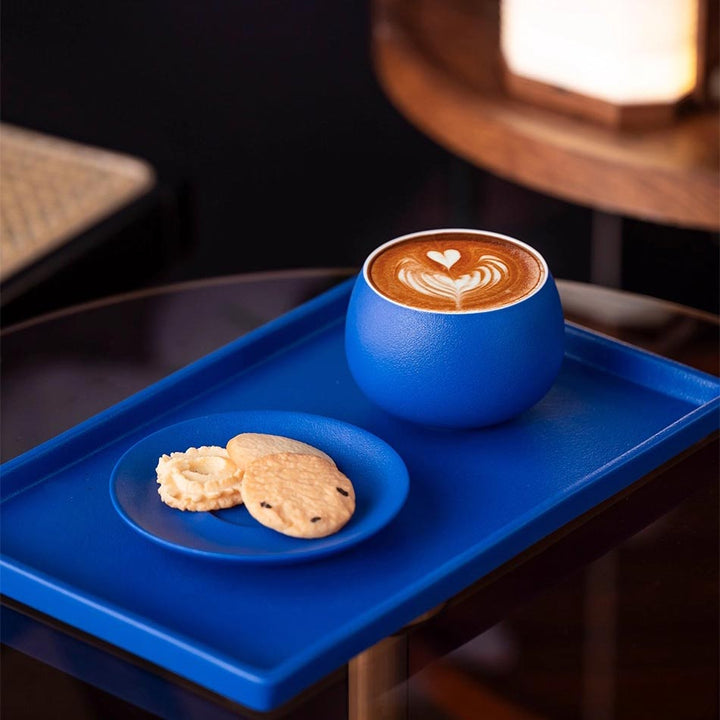 Klein blue ceramic coffee and dessert cups on tray, elegant stylish setup for refined afternoon tea