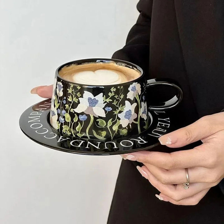 Black ceramic latte cup on desk held by woman, styled coffee setup for luxury table display