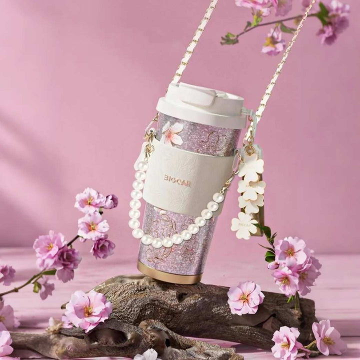 MyLaEvo natural titanium cup with sakura print and pearl chain, displayed on driftwood with pink blossoms and soft background