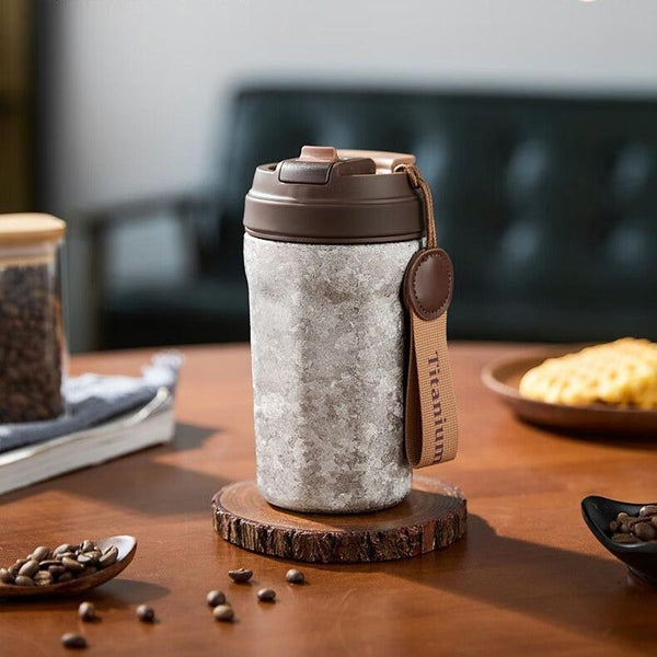 MyLaEvo grey titanium insulated coffee cup on office desk with coffee beans, modern workspace setting