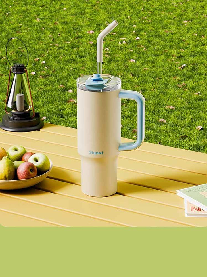 Yellow water bottle with blue handle on colorful camping table with books, fruits, and gear – MyLaEvo.