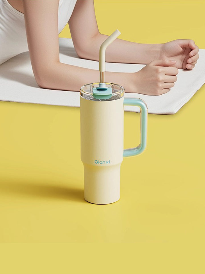 Pale yellow water bottle with blue handle placed on yellow ground near woman doing yoga – MyLaEvo.